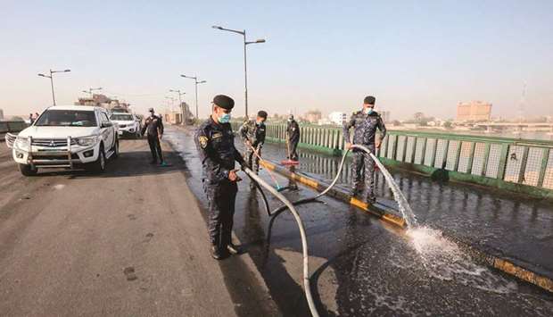 Members of the Iraqi security forces clean with a hose a section of the Jumhuriyah bridge across the Tigris River, leading from the capital Baghdadu2019s central Tahrir Square to the highly-fortified Green Zone, yesterday, as it reopens.