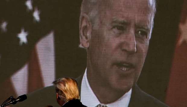 Democratic US presidential nominee and former Vice President Joe Biden is seen on a screen as US President Donald Trump watches a campaign add during his campaign rally at Green Bay Austin Straubel International Airport in Green Bay, Wisconsin, US