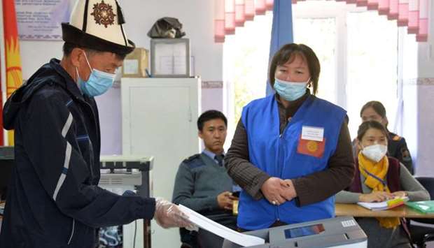 A man wearing a national 'Ak-kalpak' hat and a face mask casts his ballot at a polling station during Kyrgyzstan's parliamentary election in the village of Koy-Tash, some 20 km from Bishkek, on October 4, 2020, amid the ongoing coronavirus pandemic.