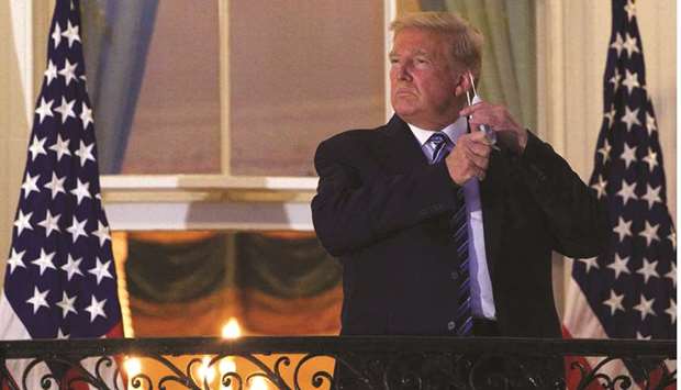 President Donald Trump takes off his face mask as he arrives at the White House upon his return from Walter Reed Medical Center, where he underwent treatment for Covid-19, in Washington, DC.