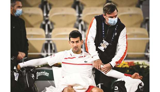 Serbiau2019s Novak Djokovic reacts as he is treated by medical staff during his French Open quarter-final against Spainu2019s Pablo Carreno Busta (not pictured) at Roland Garros in Paris, France, on Wednesday. (AFP)a