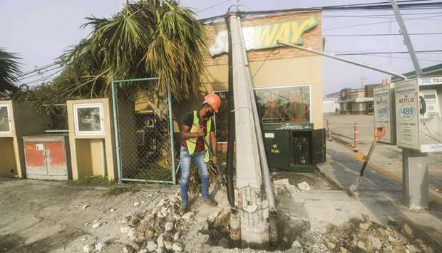 A worker repairs a street lamp post damaged by Hurricane Delta in Cancun.