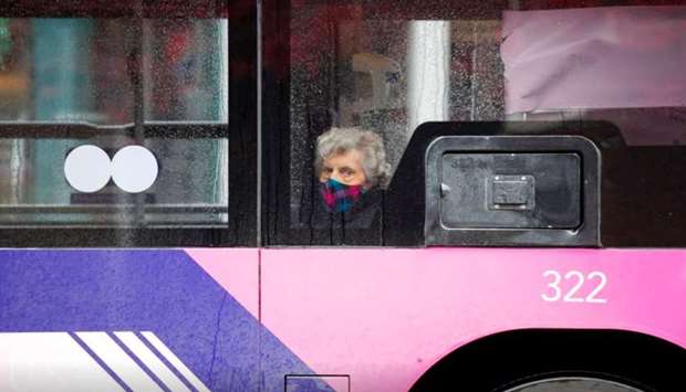 A woman wearing a face mask looks out from a window of a bus, following the outbreak of the coronavirus disease (Covid-19), in St. Albans.