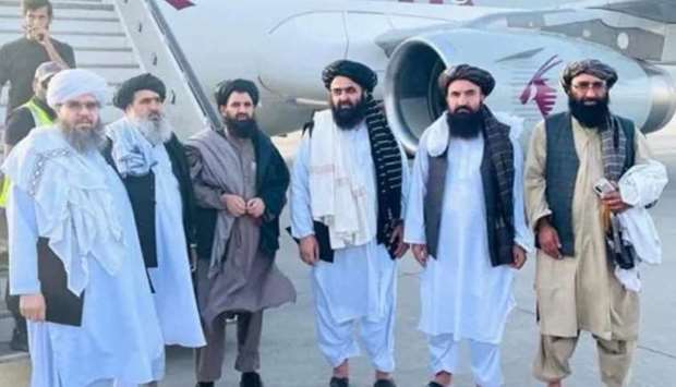 Taliban delegates stand in front of a Qatar Airways plane in an unidentified location in Afghanistan on October 8, 2021. Handout via Reuters