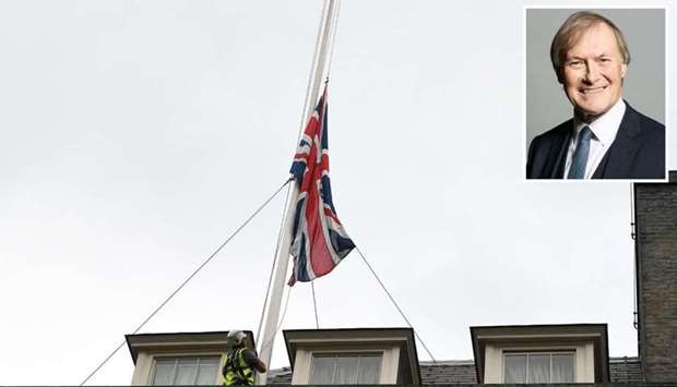 A worker lowers the British Union flag on the roof of 10 Downing Street, London, Britain, yesterday, after MP David Amess (inset) was stabbed.