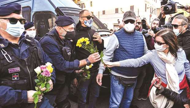 A woman hands flowers to police  officers during a protest yesterday against the so-called Green Pass at Romeu2019s Circus Maximus