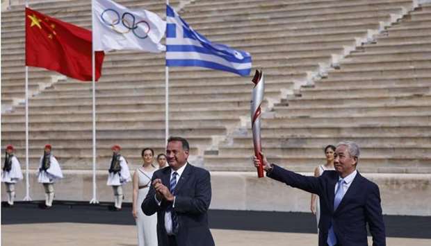 Vice-President of the Organising Committee of Beijing 2022 Winter Olympics and Paralympics and Vice-President of the International Olympic Committee Yu Zaiqing holds the torch with the flame during the ceremony as President of the Hellenic Olympic Committee Spyros Capralos looks on REUTERS