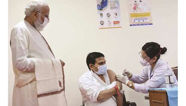 Indiau2019s Prime Minister Narendra Modi watches a health worker inoculating a man with a Covid-19 vaccine dose during his visit to a vaccination centre at Ram Manohar Lohia Hospital in New Delhi. India administered its one billionth Covid-19 vaccine dose on October 21.