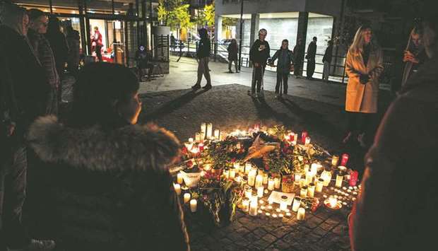 People gather to put flowers and candles at a makeshift memorial after famous Swedish rap artist Einar was shot to death late Thursday, in the Hammarby Sjostad district of Stockholm, Sweden.