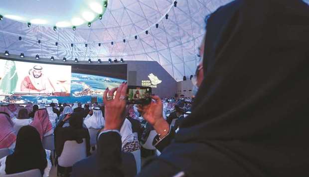 A woman records while Saudi Arabiau2019s Crown Prince Mohamed bin Salman speaks during the Saudi Green Initiative Forum to discuss efforts by the worldu2019s top oil exporter to tackle climate change in Riyadh on Saturday. Prince Mohamed and the energy minister said Saudi Arabia would tackle climate change, but also stressed the continued importance of hydrocarbons and said it would continue to ensure oil market stability.