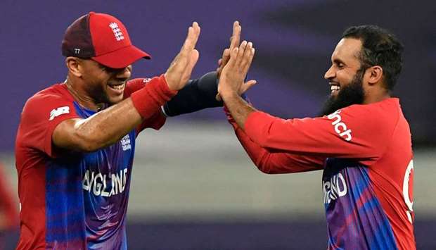 Englandu2019s Adil Rashid (right) celebrates with teammate Tymal Mills after taking the wicket of West Indiesu2019 Obed McCoy (not pictured) during the ICC menu2019s Twenty20 World Cup match at the Dubai International Cricket Stadium in Dubai yesterday. (AFP)
