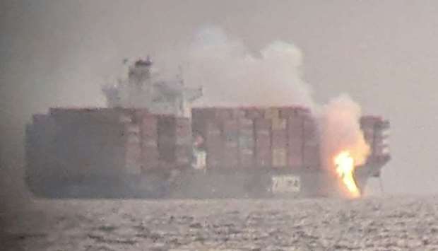 Fire cascades down from the deck of the container ship ZIM Kingston into the waters off the coast of Victoria, British Columbia, Canada, October 23, 2021, as seen through a pair of binoculars, in this image obtained via social media. PHOTO: Surfrider Foundation Canada via REUTERS