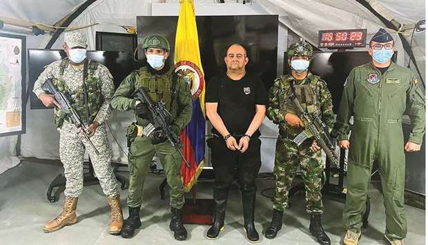 Dairo Antonio Usuga David, alias u2018Otonielu2019, top leader of the Gulf clan, poses for a photo escorted by Colombian military soldiers after being captured, in Necocli, Colombia. (Reuters)