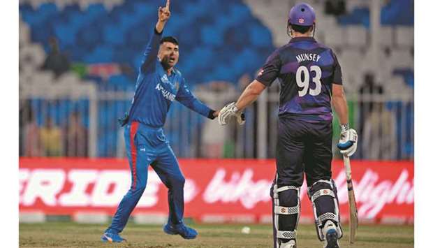 Afghanistanu2019s Mujeeb Ur Rahman (left) celebrates after taking the wicket of Scotlandu2019s Calum MacLeod (not pictured) as Scotlandu2019s George Munsey looks on during the ICC menu2019s Twenty20 World Cup match at the Sharjah Cricket Stadium in Sharjah yesterday. (AFP)