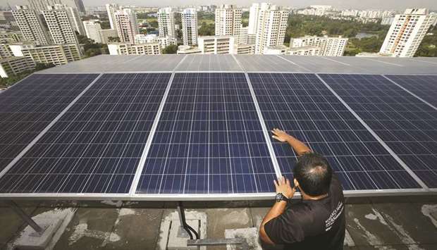 A maintenance officer inspects photovoltaic solar modules on top of a block of public housing estate apartments in Singapore (file). Asean has proposed that 23% of primary energy come from renewable sources by 2025.
