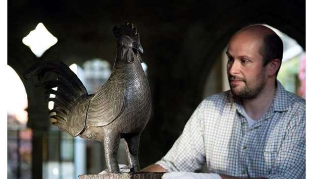 Archivist Robert Athol with a bronze statue of a cockerel called The Okukor, one of the Benin Bronzes, at Jesus College, University of Cambridge.