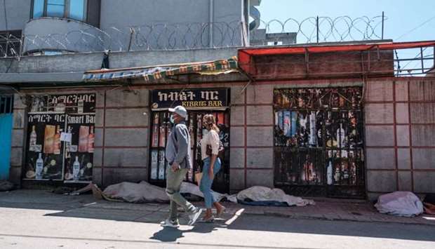 People walk in front of closed shops, in the city of Addis Ababa, Ethiopia, on October 21