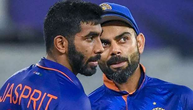 India's captain Virat Kohli speaks with teammates Jasprit Bumrah (L).