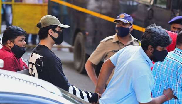 Aryan Khan (2L) is being escorted by law enforcement officials outside the Narcotics Control Bureau (NCB) office in Mumbai on October 3, 2021. 