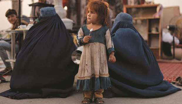 A girl stands between two women at a secondhand market in Kabul, where people trying to gather funds to leave the country sell their home appliances and other belongings.