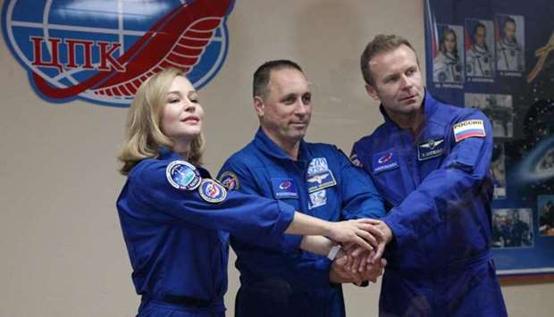 Crew members, cosmonaut Anton Shkaplerov (C), actress Yulia Peresild (L) and film director Klim Shipenko, shaking hands behind a glass wall during a news conference ahead of the expedition to the International Space Station (ISS) at the Baikonur Cosmodrome, Kazakhstan. AFP/Russian space agency Roscosmos/Andrey Shelepin