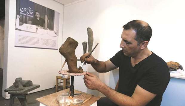 Palestinian artist Khaled Hussein works on a sculpture resembling an amputated foot in his workshop to bring attention to the plight of amputees, in Gaza City.