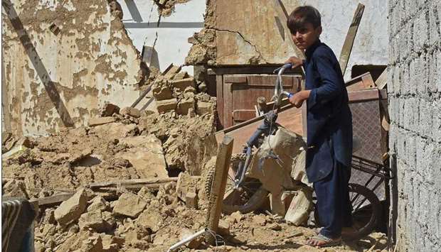 A boy holds a damaged bicycle from the rubble of collapsed houses following an earthquake in the remote mountainous district of Harnai.