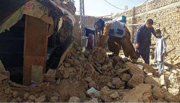 Residents gather next to the debris of their houses that collapsed following an earthquake in the remote mountainous district of Harnai on October 7, 2021. (AFP)
