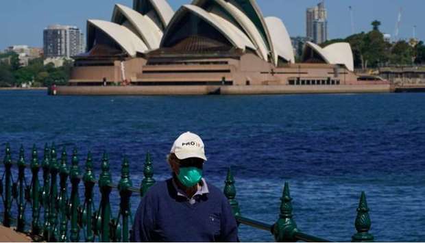 A person in protective face mask walks along the harbour waterfront across from the Sydney Opera House during a lockdown to curb the spread of coronavirus disease (Covid-19) outbreak in Sydney, Australia.