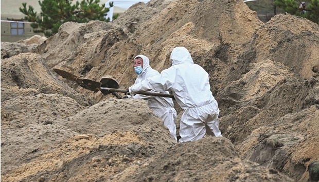 Forensics personnel exhume the body of one of more than 50 Ukrainian soldiers buried in one mass grave at a cemetery near Lyman, Donetsk region.