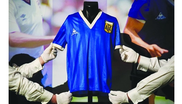 Art handlers pose with the shirt worn by Argentinian soccer player Diego Maradona in the 1986 World Cup (file picture). Reuters