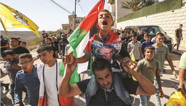 Ahmed, son of Mujahed Dawood, a Palestinian who died after being critically wounded the previous day during clashes with Israeli forces in the village of Qarawat Bani Hassan, chants slogans as he is carried on the shoulders of a man marching during the funeral in the village of Haris in the occupied West Bank, yesterday.