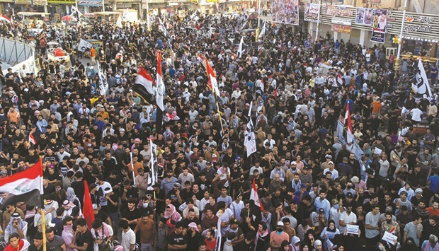 Iraqi protesters lift placards and national flags during a rally to mark three years since nationwide demonstrations erupted against endemic corruption, at Al-Habboubi square in the southern city of Nasiriyah, on Saturday.