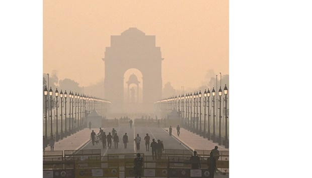 People walk along a road near India Gate amid smoggy conditions in New Delhi yesterday.