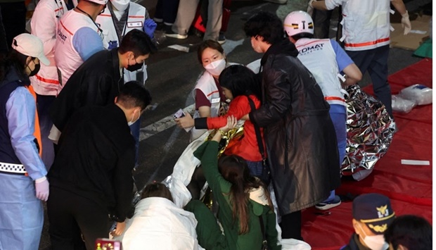 People receive medical help from rescue team members at the scene of the stampede in Seoul, South Korea