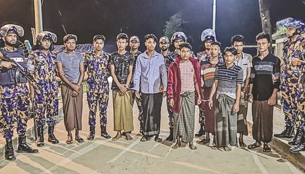 Detained Rohingya refugees next to security personal after a crackdown at the Rohingya refugee camp in Ukhia, Bangladesh.