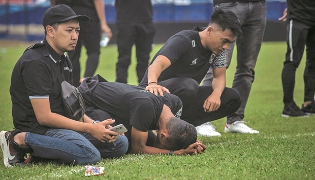 Players and officials from Arema Football Club gather to pray on the pitch for victims of the stampede at Kanjuruhan stadium in Malang, East Java, yesterday. Anger against police mounted in Indonesia after at least 125 people were killed in one of the deadliest disasters in the history of football, when officers fired tear gas in a packed stadium, triggering a stampede. (AFP)