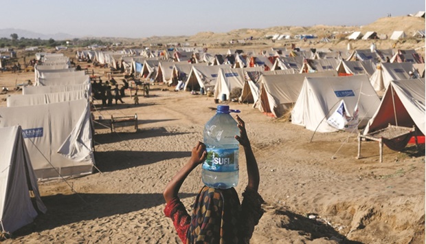 A girl carries a bottle of water that she filled from nearby stranded floodwaters, at a camp in Sehwan, Pakistan, where her family has taken refuge.