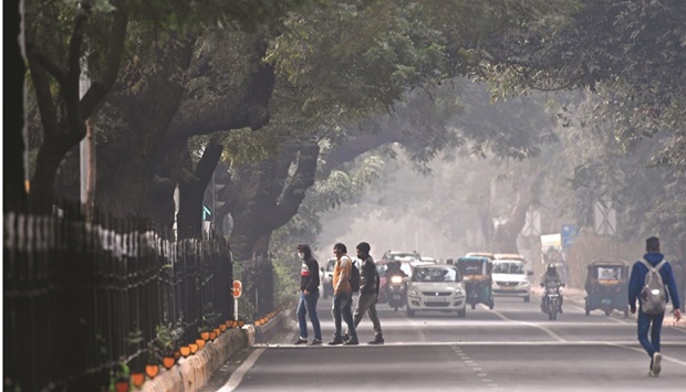 Commuters cross a road amid smoggy conditions in New Delhi (file). While Indiau2019s economy posted double-digit growth in the April-June quarter, the RBIu2019s aggressive monetary policy tightening is seen as a risk to demand in an economy where consumption accounts for some 55% of growth.