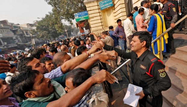 A security guard hands out request slips for the exchange of old high denomination bank notes at a branch of the State Bank of India in Old Delhi