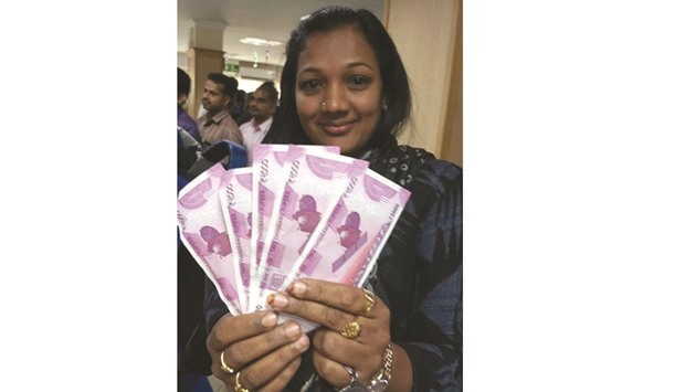 A woman displays new Rs2,000 notes as she poses outside a bank in Thiruvananthapuram yesterday.