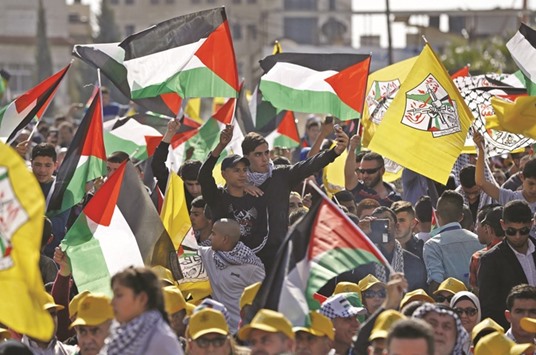 Palestinians wave their national flag and Fatah party flags at a rally marking the 12th anniversary of the death of Yasser Arafat in the West Bank city of Ramallah yesterday.