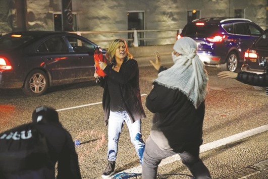 A motorist who was caught in the middle of a riot threatens a demonstrator with detergent during a protest against the election of Republican Donald Trump as president of the US in Portland, Oregon.
