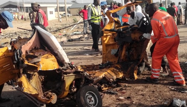This October 29, 2016 file picture shows emergency personnel standing near the wrecked remains of a vehicle ripped apart following two suicide bombings in Maiduguri.