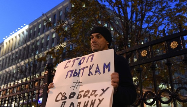 A man holds a placard reading ,Stop torture, Freedom for Dadin, as he pickets Russia's Federal Penitentiary Service in Moscow. AFP