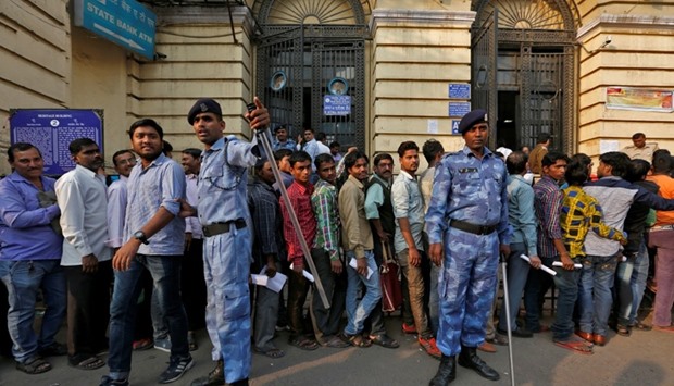 Riot police control people queueing to exchange old high denomination bank notes at a bank in Old Delhi, India.