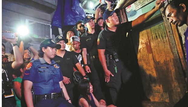 Funeral parlour workers, policemen, reporters and the relatives of a person who was killed, wait for investigation to be done outside a house in Manila yesterday.