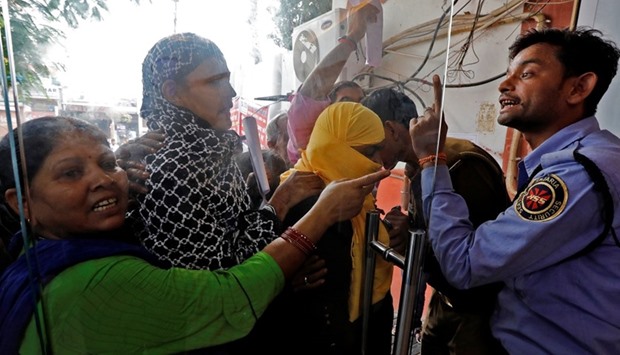 A security guard argues with a woman at a bank's entrance gate in Lucknow, India