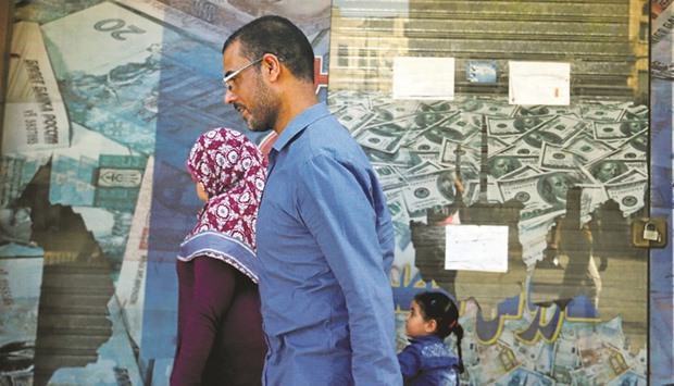 People walk past an exchange bureau in Cairo. The IMFu2019s $12bn loan programme may restore investor confidence in Egypt and help revive an economy battered by years of political turmoil.