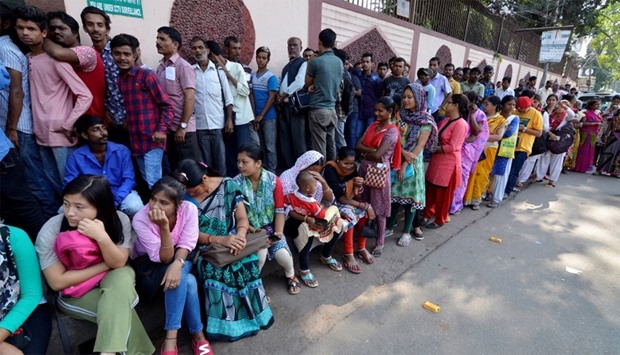 People queue to exchange and deposit their old high denomination banknotes outside a bank